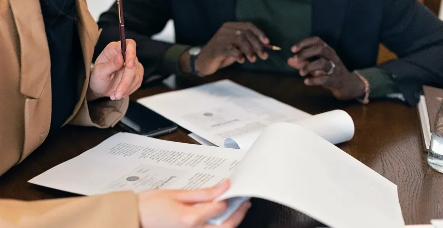 Duas pessoas revisando documentos fiscais impressos sobre uma mesa